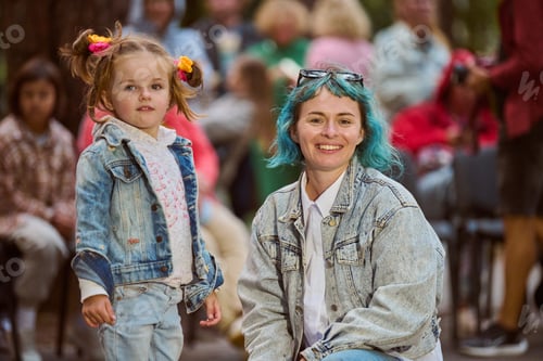 Preview: Smiling young woman with child in denim outdoors