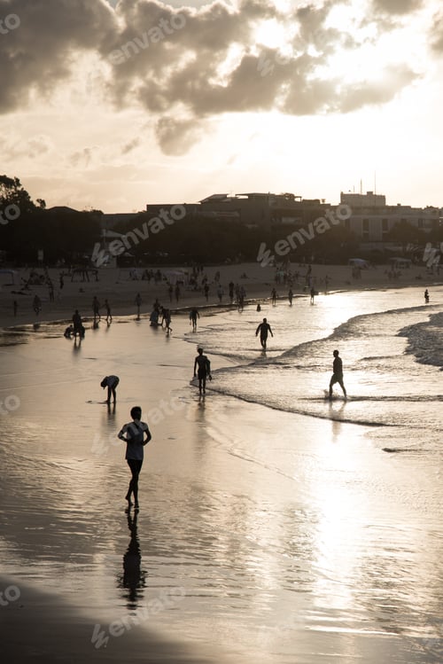 People Enjoying Sunset on Beach Along City Coastline