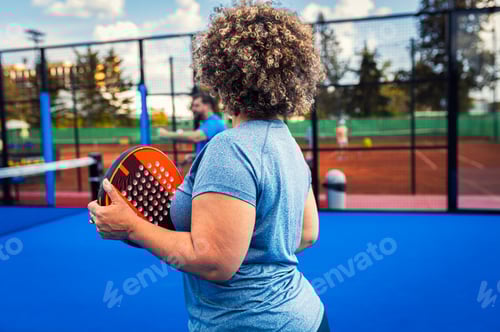Preview: Rear view of woman playing padel with her friend on outdoor court.