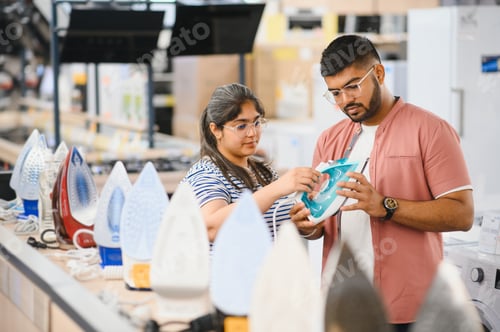 Preview: Indian Couple standing in an electronics store choosing an electric iron for Ironing things