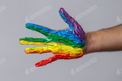 Preview: Male Hand Covered in Rainbow Paint on Gray Background