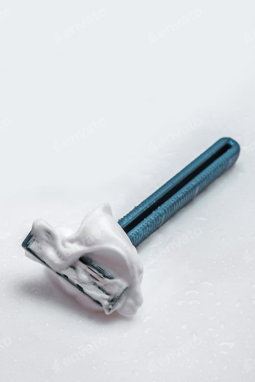 Preview: Shaving Razor with Foam on White Surface