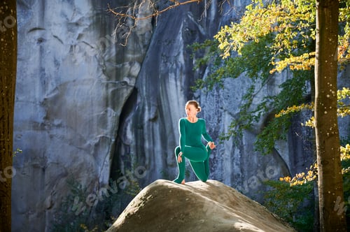 Preview: Woman practicing yoga outdoors in forest. Barefoot female on yoga mat surrounded by trees and rocks