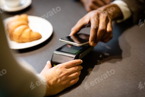 Preview: Afro businessman paying with cellphone at the bar