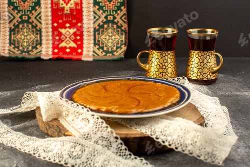 Preview: a front view sweet delicious halva yummy eastern sweet dessert inside plate with tea on the dark