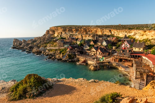 Preview: Il-Mellieha, Malta - Panoramic skyline view of the famous Popeye Village at Anchor Bay at sunset
