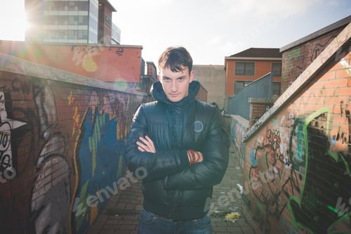 Preview: Half length of young handsome caucasian man posing outdoor in the city back light