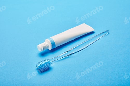 Preview: close up view of toothbrush and toothpaste arranged on blue backdrop, dentistry concept