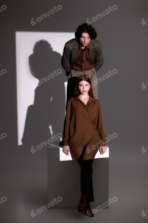 Preview: Chic young couple gracefully posing in a stylish dark grey studio setting