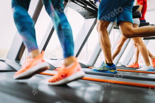 Preview: Healthy man and woman running on a treadmill in a gym