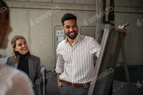 Preview: Cheerful young businesspeople standing and working in office, cooperation and brainstorming concept