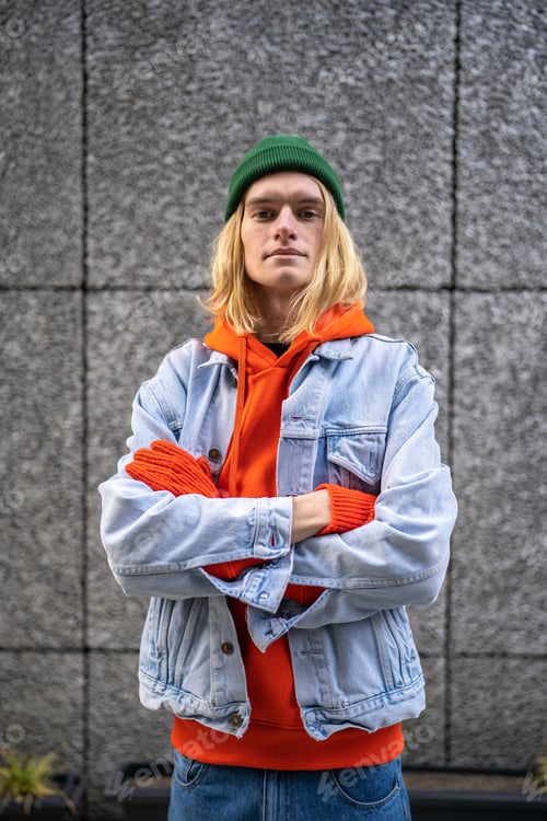 Preview: Street portrait of stylish European millennial hipster guy posing against gray concrete wall