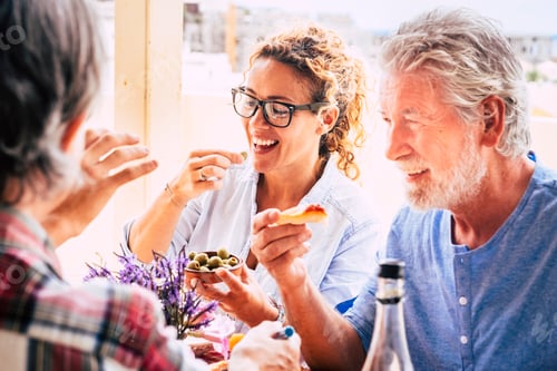 Preview: People having fun together during lunch in friendship - mixed ages woman and an eating in family