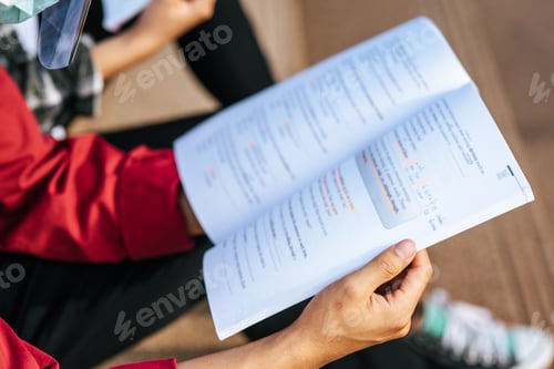 Preview: A male student wearing a mask and sitting reading.