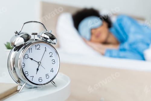 Preview: alarm clock near blurred african american woman in bed