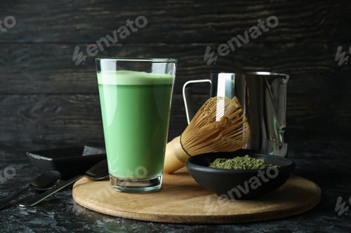 Preview: Glass of matcha latte and accessories for making on black smokey table