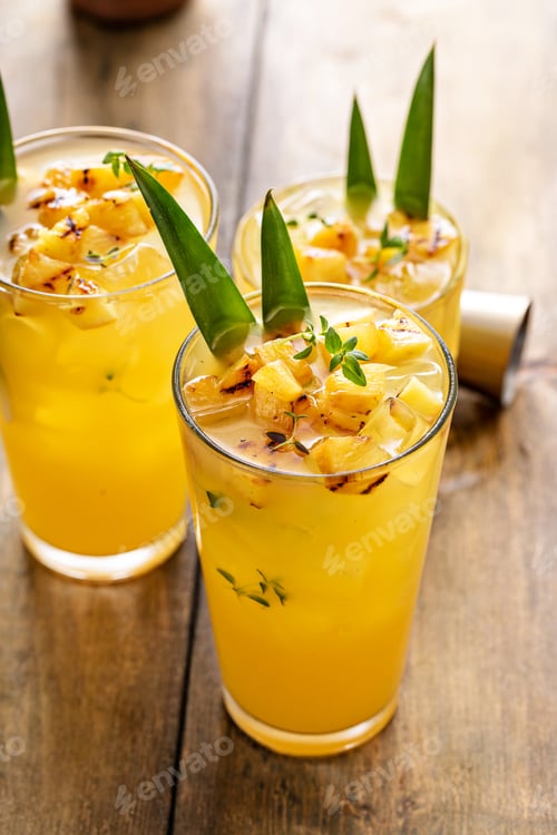 Preview: Grilled pineapple cocktail in tall glasses garnished with pineapple leaves