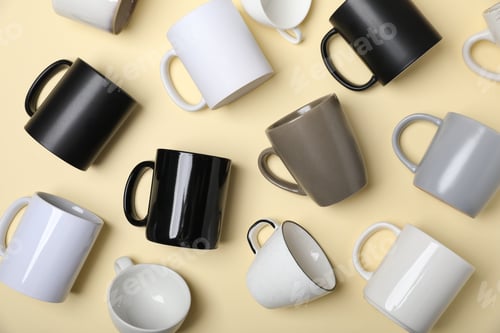 Preview: Many different cups on pale yellow background, flat lay