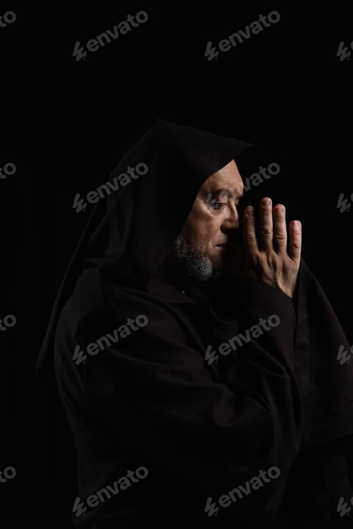 Preview: side view of medieval abbot in hood praying isolated on black