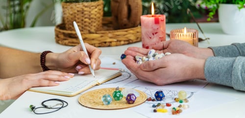 Preview: Numerology Divination consultation: woman writing in a notebook, man holding fortune stones.
