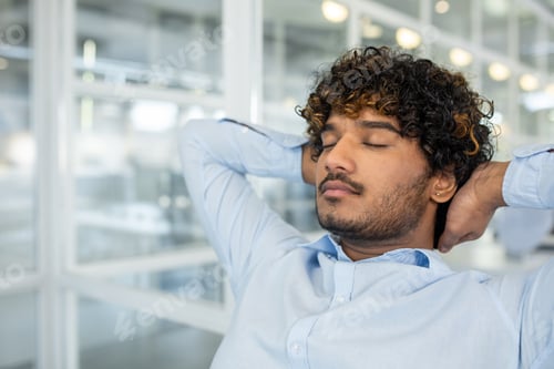Preview: Young businessman relaxing with eyes closed in modern office