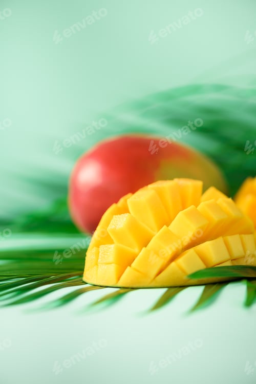 Preview: Exotic mango fruit over tropical green palm leaves on turquoise background. Copy space. Pop art