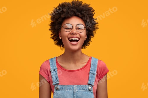 Vista previa: Glad African American female with positive expression, laughs joyfully as watches funny movie with f