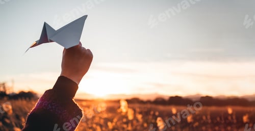Preview: Traveling woman with paper airplane plays at the land at sunset.