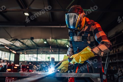 Preview: Young man welding a piece of metal while making a metal construction.