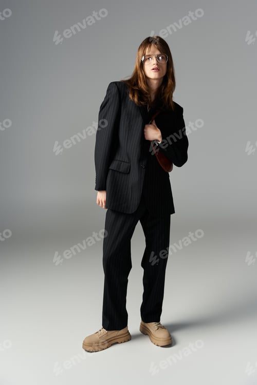 Preview: A young stylish individual poses confidently in modern attire against a minimalist backdrop