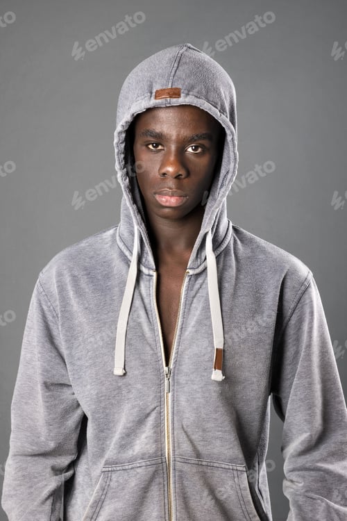 Preview: Young black man in hoodie standing and looking at camera in studio