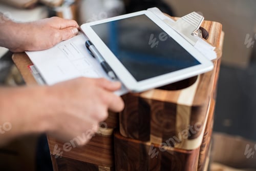 Preview: Man using digital tablet to check wooden products in factory