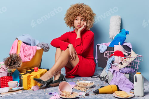 Preview: Unhappy stressed lady wears red dress and black high heeled shoes sits on floor against different