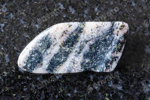 Preview: sample of tumbled gneiss rock on black granite