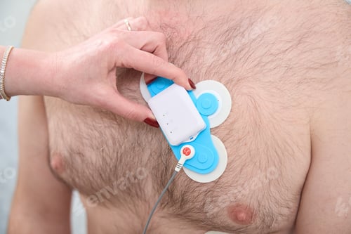 Preview: Close up of cardiologist examining male patient with holter device