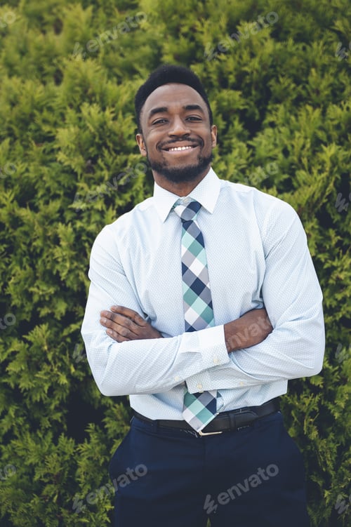 Preview: Vertical shot of a handsome African-American male posing on a green thuja background