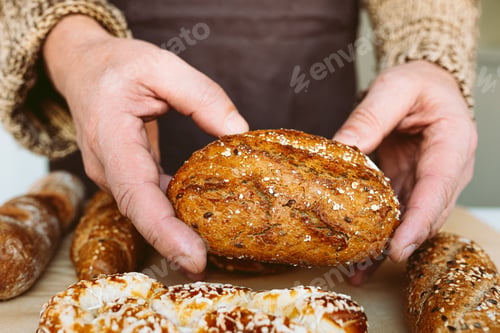 Preview: Close-up of male hands holding freshly baked bread on wooden table