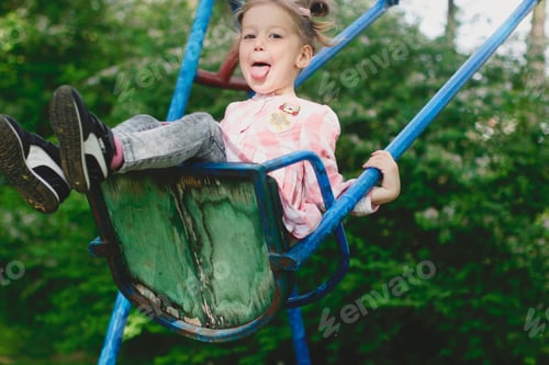 Preview: pretty little girl swinging in the park and showing her tongue
