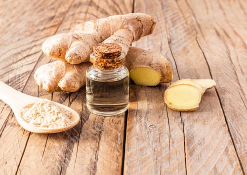 Preview: Ginger root essential oil in a glass bottle with a cork cap on a wooden table with root