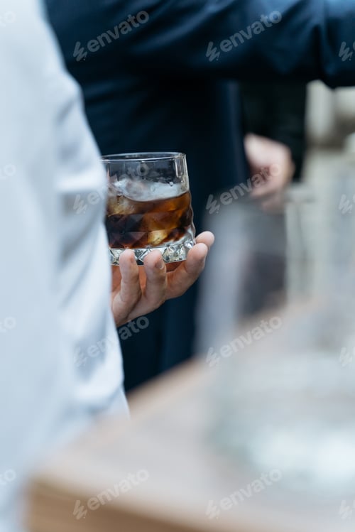 Preview: Man holding glass with whiskey on the party