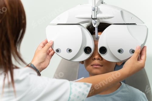 Preview: Asian boy with a phoropter at an optometrist consultation