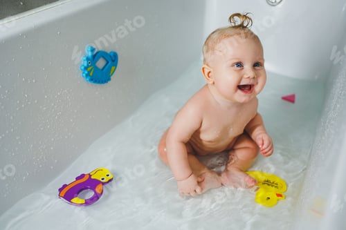 Preview: A little boy of 6 months with a ponytail on his hair is bathing in the bathroom. Bathing a baby
