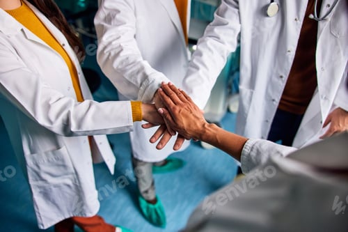 Preview: Close-up of a team of united doctors with folded hands in the surgery room.