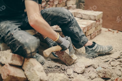 Preview: A young man cleans bricks with an axe.