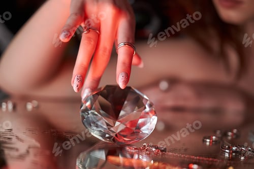 Preview: Beauty Woman holds big diamond in hand while lying on table. Beautiful hands, professional manicure