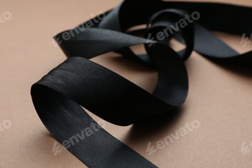 Preview: Beautiful black ribbon on light brown background, closeup
