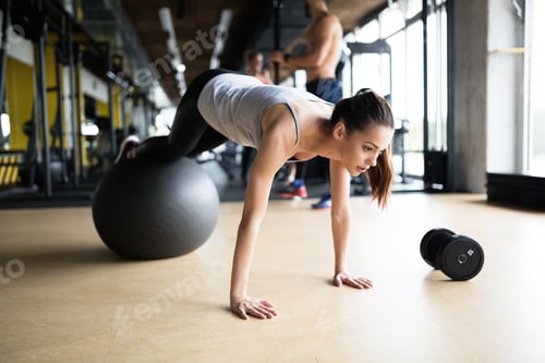 Preview: Athletic woman exercising in gym