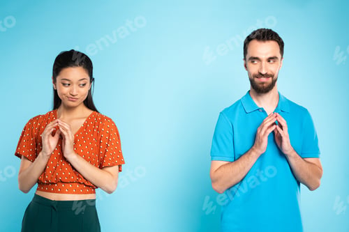 Preview: skeptical asian woman in red blouse and sly man in polo t-shirt gesturing with joined fingers on