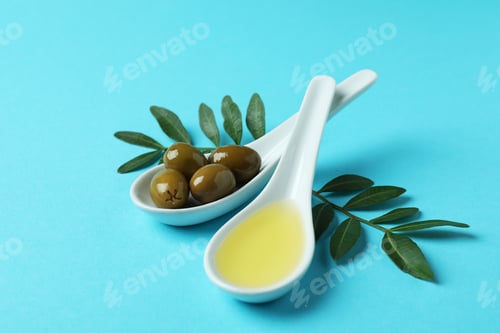 Preview: Spoons with olives and oil, and twigs on blue background
