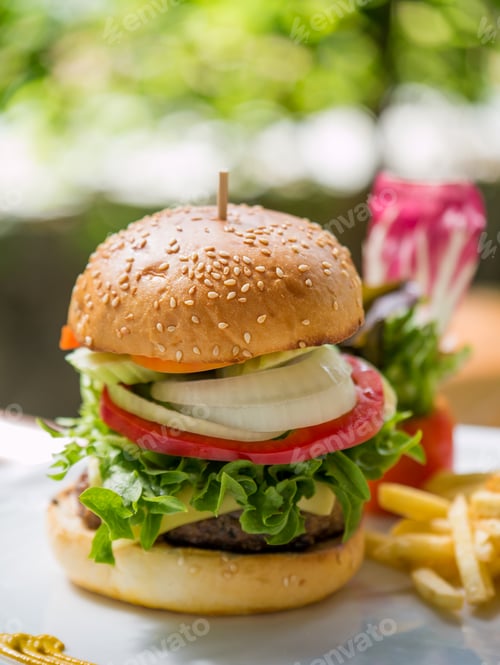 Preview: Classic deluxe cheeseburger with lettuce, onions, tomato and pickles on a sesame seed bun.